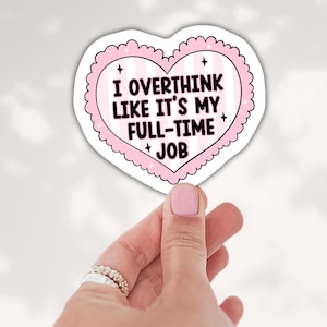 May include: A heart-shaped sticker with a scalloped pink border and a light pink and white striped background. The text reads I OVERTHINK LIKE IT'S MY FULL-TIME JOB in bold black letters, accented by small black four-pointed star icons.