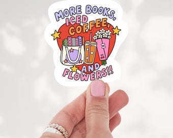 May include: A die-cut sticker featuring a red heart background with the text MORE BOOKS, ICED COFFEE, AND FLOWERS. The design includes a tote bag filled with books, a plastic cup of iced coffee, and a bouquet of white daisies with cherry icons.
