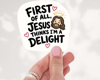 May include: A white die-cut sticker featuring the black text "FIRST OF ALL, JESUS THINKS I'M A DELIGHT" with a cartoon illustration of Jesus wearing a yellow halo, accented by three small pink hearts surrounding the lettering.