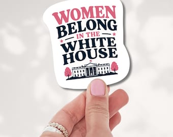 May include: A white die-cut sticker featuring the text WOMEN BELONG IN THE WHITE HOUSE in pink and dark blue lettering, accented by two small pink stars and a graphic illustration of the White House flanked by two pink trees.
