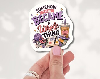 May include: A die-cut sticker featuring the text SOMEHOW THIS BECAME A WHOLE THING with illustrations of a purple yarn ball, scissors, a notebook labeled IDEAS, a glue stick, and an iced coffee cup with a heart sticker reading FUELING THE CHAOS.