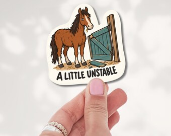 May include: A die-cut sticker featuring a brown horse with a dark mane standing next to a broken teal wooden gate. The horse has a tired expression and is chewing hay. Below the illustration, the text reads A LITTLE UNSTABLE in black.