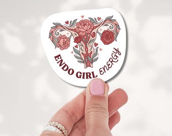 May include: A white die-cut sticker featuring a stylized anatomical uterus illustration adorned with pink and red floral patterns, green leaves, and small hearts, with the text "ENDO GIRL ENERGY" printed in a dark red, curved font.