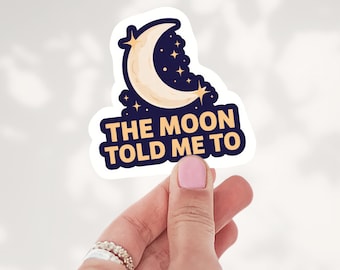 May include: A die-cut sticker featuring a cream-colored crescent moon against a dark navy blue background with small yellow stars. The text THE MOON TOLD ME TO is printed in bold yellow capital letters at the bottom of the sticker.
