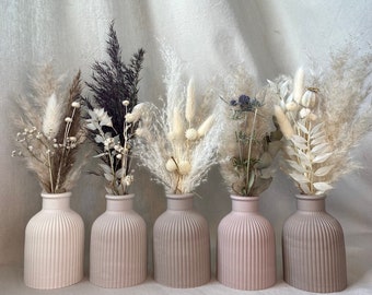 May include: Five small, light gray, ribbed ceramic vases with different dried flower arrangements. The flowers are white, cream, and light purple.