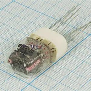 May include: A vintage vacuum tube with a clear glass enclosure and a white ceramic base. The tube has several silver wire leads extending from the base. The internal components are visible, including a dark component and pink and red wires. The tube is on a grid paper background.