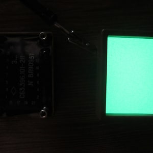 Może przedstawiać: Czarny element elektroniczny z nadrukowanym tekstem "N BJ90957 CB3396101-211". W tle widoczny jest zielony ekran.