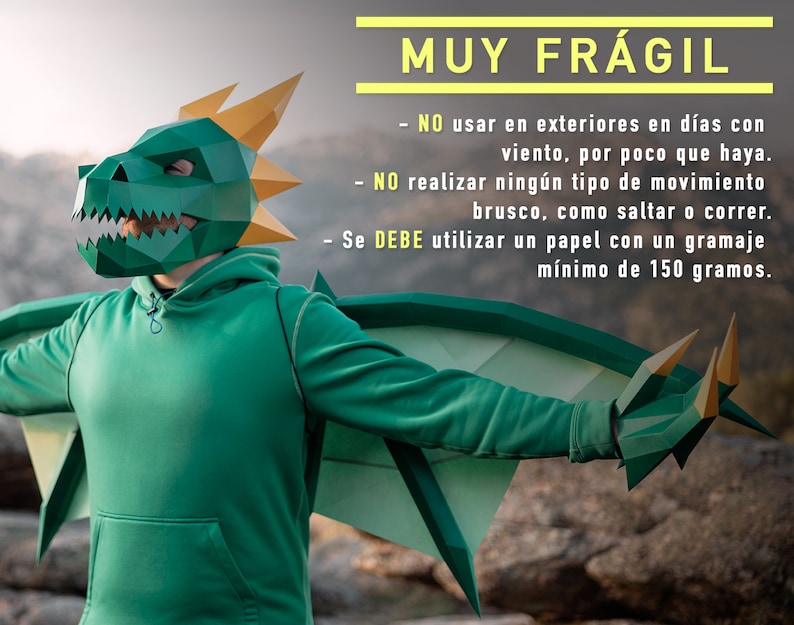May include: A person wearing a green paper dragon mask and wings. The text on the image reads: "MUY FR&Aacute;GIL - NO usar en exteriores en d&iacute;as con viento, por poco que haya. - NO realizar ning&uacute;n tipo de movimiento brusco, como saltar o correr. - Se DEBE utilizar un papel con un gramaje m&iacute;nimo de 150 gramos."