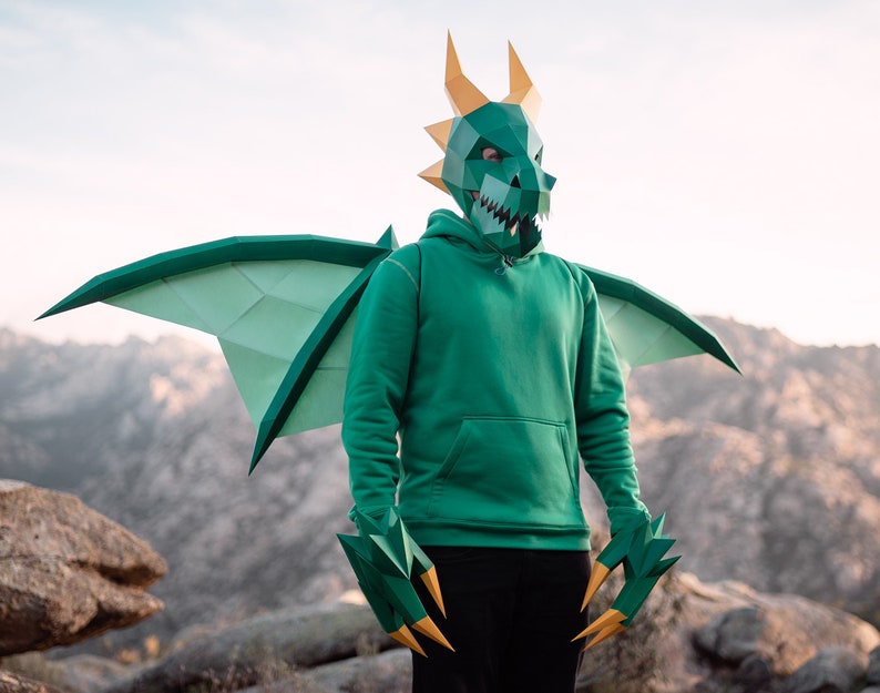 May include: A person wearing a green dragon costume with wings and claws. The costume is made of paper and has a realistic design.