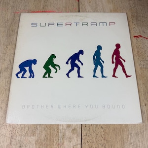 May include: A white vinyl record sleeve featuring the text SUPERTRAMP at the top and BROTHER WHERE YOU BOUND at the bottom. The center displays a colorful evolution graphic showing five figures in blue, green, dark blue, teal, and magenta.
