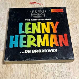 May include: A vintage vinyl record album cover for "Lenny Herman...On Broadway." The black cover features the text "The King of Stereo" and the artist's name in colorful, bold letters. A crown graphic is at the top.