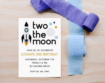 Könnte beinhalten: Eine blaue und weiße Raketenillustration mit dem Text "two the moon" in Schwarz und Gold. Die Einladung ist für Logans 2. Geburtstagsparty, mit Datum, Uhrzeit und Adresse darunter.