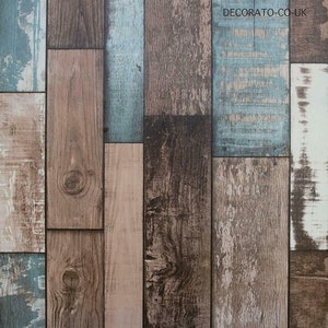 May include: A wood-look wallpaper with a rustic design featuring a variety of wood tones, including brown, beige, and blue. The wallpaper has a distressed look, giving it a vintage feel. The text "DECORATO-CO-UK" is printed in the upper right corner.