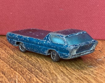 May include: A vintage blue toy car with a pickup truck bed. The die-cast metal vehicle has silver wheels and a weathered appearance. The toy car is on a wooden surface.