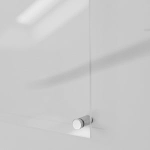 May include: A clear acrylic panel is mounted on a white wall with a silver-colored standoff. The standoff has a cylindrical body and a flat, white head. The panel's edge is visible, showing its transparency.
