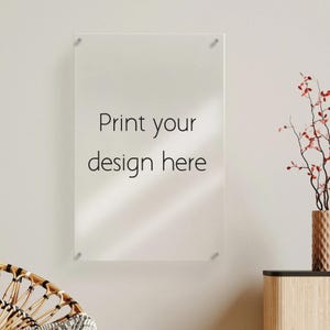 May include: A clear acrylic print with the text "Print your design here" in black. The print is mounted on a light-colored wall with silver hardware. A decorative vase with red branches is visible.