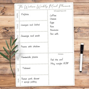 May include: A white weekly meal planner with the text "The Watson Weekly Meal Planner." The planner includes sections for each day of the week, a shopping list, and notes. A black and white marker is on the right.