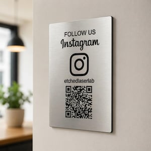 May include: A rectangular brushed metal sign with the words "FOLLOW US" above the word "Instagram" and an Instagram logo. Below the logo is the text "etchedlaserlab" and a QR code.