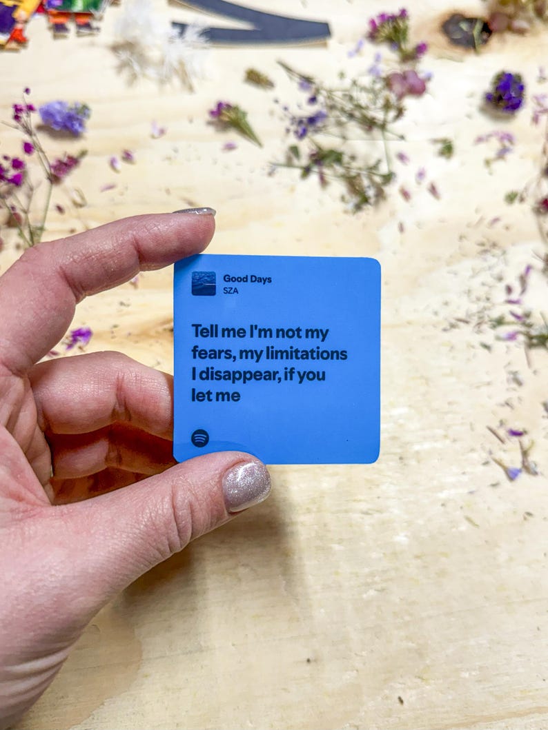 Op de afbeelding: Een blauwe vierkante sticker met de tekst "Good Days" van SZA. De sticker bevat ook de tekst "Tell me I'm not my fears, my limitations I disappear, if you let me."