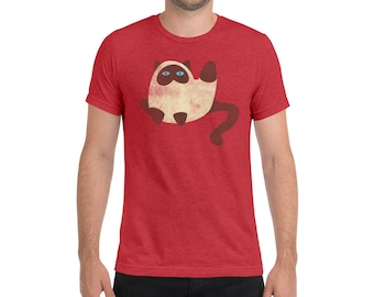 May include: Red t-shirt featuring a cartoon cat design. The cat is beige with brown accents, blue eyes, and a long brown tail. The t-shirt is made of a soft, textured fabric.