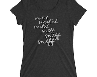 May include: A dark heather grey women's t-shirt with the words "scratch scratch scratch sniff sniff sniff" written in a white script font.