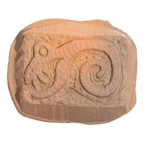 May include: A rectangular terracotta mold featuring a relief carving of a coiled snake with textured scales and a circular eye. The surface displays a natural reddish-brown clay finish with visible carved details and the letters PBULI at the bottom.