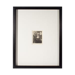 May include: A framed black and white print. The print is a small, detailed image of a group of people. The frame is black and has a simple, classic design. The print is centered within a white mat.