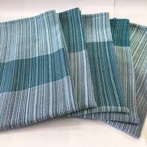 Könnte beinhalten: Satz mit fünf Küchenhandtüchern in Teal und Weiß. Die Handtücher sind mit einer dezenten Textur gewebt und haben ein weiches, saugfähiges Gefühl.