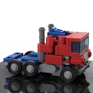 Pode incluir: Um modelo de caminhão Lego vermelho, azul e cinza. O caminhão tem uma cabine com um pára-brisa e um reboque de plataforma. O caminhão tem quatro rodas e está sobre uma superfície preta.