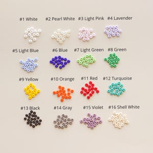 Peut inclure: Seize groupes de petites perles rondes et color&eacute;es dispos&eacute;es en grille. Chaque groupe est &eacute;tiquet&eacute; avec un num&eacute;ro et un nom de couleur : #1 White, #2 Pearl White, #3 Light Pink, #4 Lavender, #5 Light Blue, #6 Blue, #7 Light Green, #8 Green, #9 Yellow, #10 Orange, #11 Red, #12 Turquoise, #13 Black, #14 Gray, #15 Violet et #16 Shell White.