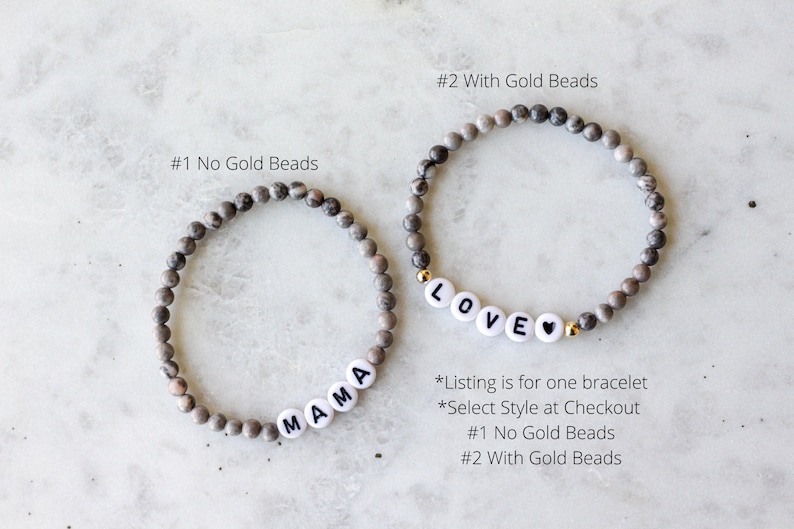 May include: Two beaded bracelets made of grey and brown mottled stone beads. One bracelet features white letter beads spelling MAMA. The other bracelet features white letter beads spelling LOVE with a heart symbol and small gold-colored accent beads.