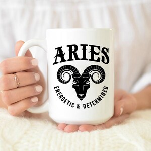 May include: White ceramic mug with a black and white graphic of an Aries zodiac sign. The text "Aries Energetic & Determined" is printed on the mug.