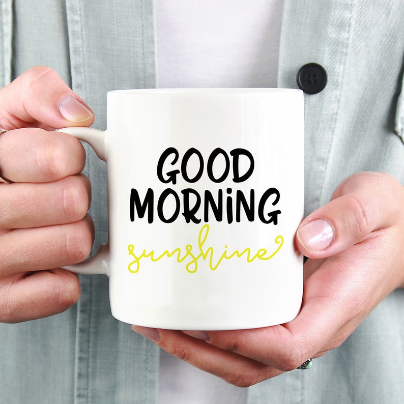 Puede incluir: Taza de cer&aacute;mica blanca con texto negro que dice "GOOD MORNING sunshine" en una fuente cursiva amarilla.