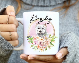 May include: White ceramic mug with a watercolor illustration of a white West Highland Terrier dog with pink flowers and a gold circle with the name "Kingsley" written in black.
