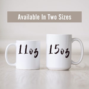 May include: Two white ceramic mugs with black handwritten text. The mug on the left says "11oz" and the mug on the right says "15oz".