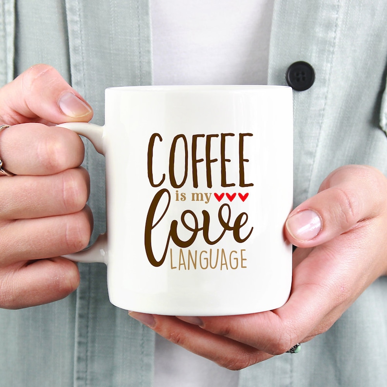 May include: White ceramic coffee mug with brown text that reads "Coffee is my love language" with three red hearts.