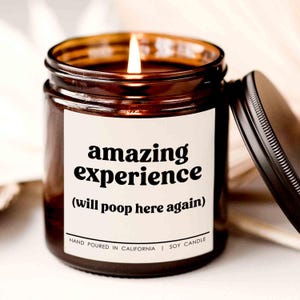 May include: A brown glass candle with a white label that reads "amazing experience (will poop here again)". The candle is hand-poured in California and is a soy candle.