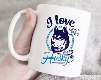 May include: White ceramic mug with a blue and white design. The mug features a husky dog with the text "I love my Husky" in a blue and white font.