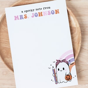 May include: A white ghost with a pink bandana and a pumpkin bucket holds a purple pencil. The ghost is in front of a rainbow with bats flying around it. The text "a spooky note from MRS. JOHNSON" is at the top of the page.