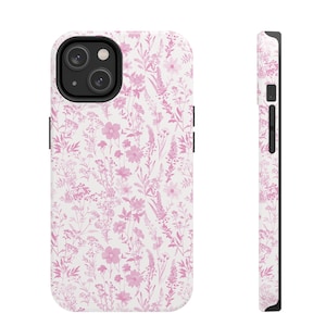 Puede incluir: Una funda de teléfono blanca con un patrón floral rosa. La funda tiene un recorte para la lente de la cámara.