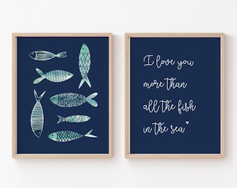 Könnte beinhalten: Zwei gerahmte Drucke mit einem marineblauen Hintergrund. Der linke Druck zeigt eine Reihe von blauen und grünen Fischen mit weißen Umrissen. Der rechte Druck zeigt den Text "Ich liebe dich mehr als alle Fische im Meer" in weißer kursivschrift mit einem kleinen Herzen am Ende.