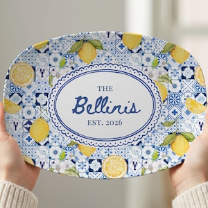 May include: Oval serving platter with a blue and white tile pattern, lemons, and floral accents. The center features an oval with the text "The Bellinis EST. 2026" in blue script. A decorative piece for serving.