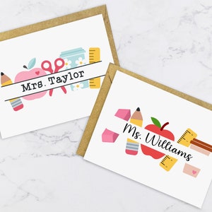 May include: Two teacher appreciation cards with a brown envelope. The cards feature a white background with colourful school supplies and the text "Mrs. Taylor" and "Ms. Williams".