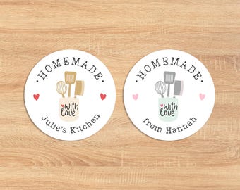 May include: Two round white stickers with the text "HOMEMADE." in black. One sticker has a light green background with the text "with love" and "from Hannah". The other sticker has a light brown background with the text "with love" and "Julie's Kitchen". Both stickers have a cartoon image of a jar with kitchen utensils.