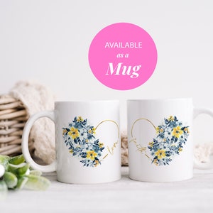 May include: Two white ceramic mugs with a heart-shaped floral design. The heart is outlined in gold and filled with blue and yellow flowers. One mug says "love" and the other says "faith". The text "AVAILABLE as a Mug" is in a pink circle.