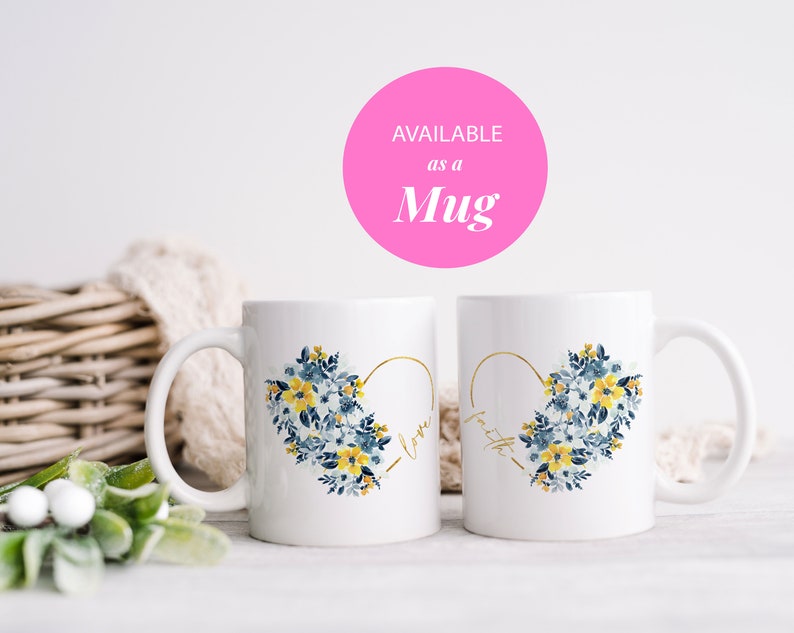 May include: Two white ceramic mugs with a heart-shaped floral design. The heart is outlined in gold and filled with blue and yellow flowers. One mug says "love" and the other says "faith". The text "AVAILABLE as a Mug" is in a pink circle.