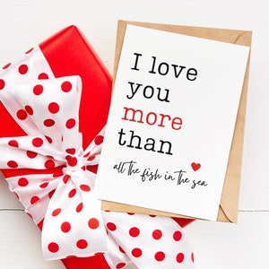 May include: A red gift box with white polka dots and a white ribbon tied in a bow. A card with the text "I love you more than all the fish in the sea" is on top of the box.
