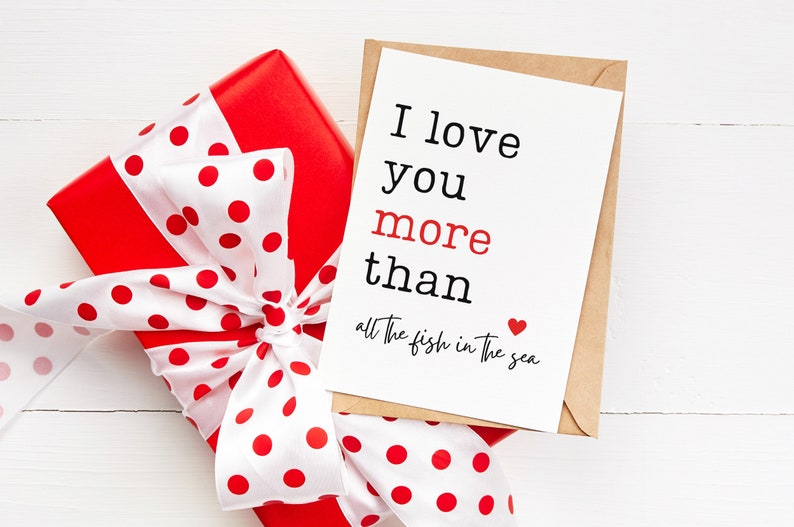 May include: A red gift box with white polka dots and a white ribbon tied in a bow. A card with the text "I love you more than all the fish in the sea" is on top of the box.