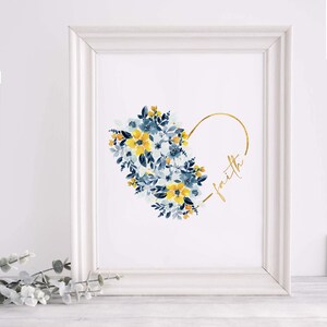May include: A framed art print featuring a watercolor floral heart design. The heart is composed of blue and yellow flowers. The word "faith" is written in gold script within the heart's outline. The frame is white.