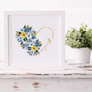 May include: A framed art print featuring a watercolor floral heart design. The heart is composed of blue and yellow flowers, with a gold outline and the word "faith" in gold script. The frame is white.
